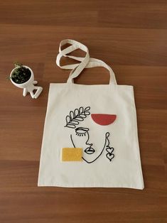 a white bag sitting on top of a wooden floor next to a potted plant