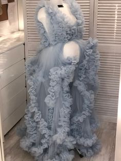 a dress made out of tulle and fabric on display in a room with shutters