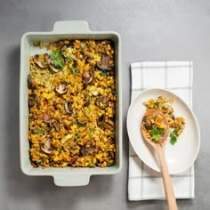 a casserole dish with mushrooms and parsley next to a spoon on a plate