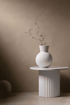 a white vase sitting on top of a table