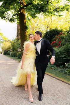 a man in a tuxedo kissing a woman in a yellow feathered dress