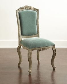 an antique style chair with blue velvet upholstered back and arms, sitting on a wood floor