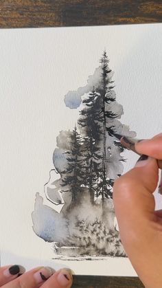 a person is painting trees with watercolors on paper