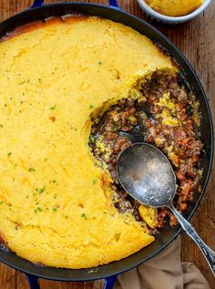 a skillet filled with food on top of a wooden table next to a bowl