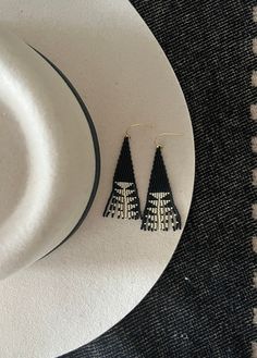 three black and white triangle shaped earrings sitting on top of a plate