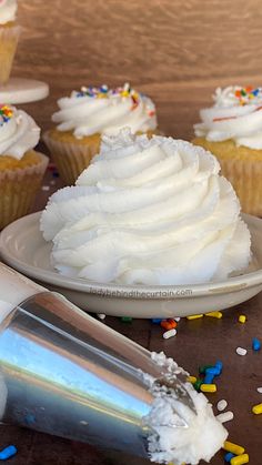 cupcakes with white frosting and sprinkles are on the table