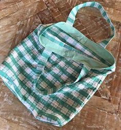 a green and white checkered bag sitting on top of a wooden table next to a pair of scissors