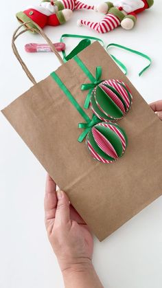 a person holding a brown paper bag with green and red decorations on it, next to some candy canes