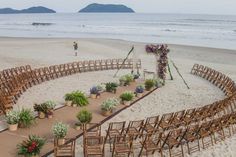 an outdoor ceremony setup on the beach with wooden chairs and flower arrangements arranged in rows