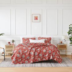 a bed with red and white bedspread in a room next to a potted plant