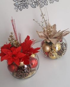 two vases filled with christmas decorations on top of a white table next to a wall