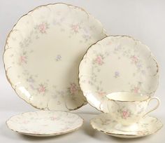 an antique china dinner set with pink flowers on the rims and saucers,