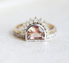 an engagement ring with a large pink stone surrounded by small white stones and gold trimmings