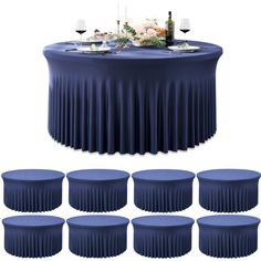 a round table covered in blue cloths with wine glasses and flowers on the top