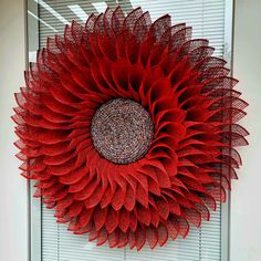 a large red sunflower hanging on the side of a wall next to a window