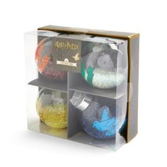 three clear boxes with different colored ornaments inside each box, one containing a harry potter ornament and the other containing a hogwart