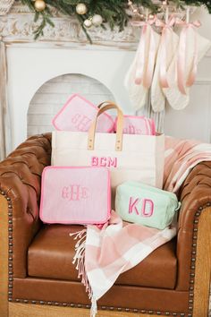 personalized tote bags sitting on a chair in front of a fireplace with pink and green accessories