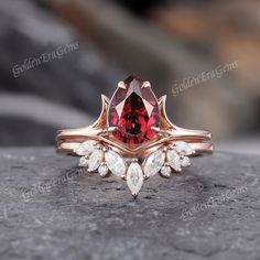 a red and white diamond ring sitting on top of a gray stone surface with leaves around it