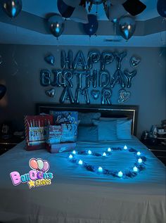 a birthday bed with blue lights on it and balloons in the shape of a heart