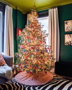 a brightly lit christmas tree in a living room with zebra print rug and green walls