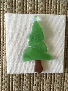 a small green christmas tree sitting on top of a piece of paper next to a white towel