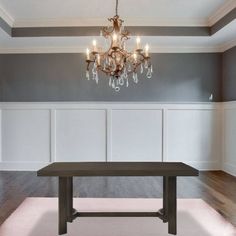 a chandelier hangs from the ceiling above a dining table in an empty room