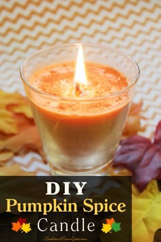 a pumpkin spice candle sitting on top of a table next to fall leaves and an orange leaf