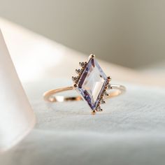 a ring with an amethorate surrounded by small diamonds on a white cloth