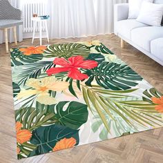 an area rug with tropical leaves and flowers on it in front of a white couch