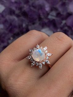 a woman's hand with an opal and diamond ring on top of it