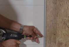 a man using a power drill to fix a wall