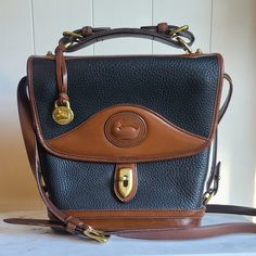 This Vintage Dooney & Bourke Carrier Bag Is In Gorgeous Condition Inside And Out, With Normal Signs Of Occasional Wear. No Rips (Other Than The D&B Tag) And No Odor. Color: Awl Black Pebbled Leather & British Tan Measurements: 9.5 Inches Tall 9.5 Inches Wide (At The Top) 3.25 Inches Deep Black Pebbles, Dooney & Bourke Bags, Carrier Bag, Dooney Bourke, Pebbled Leather, Black And Brown, Bag Lady, Handbags, Leather