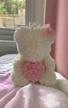 a teddy bear with a tiara on it's head sitting on a bed