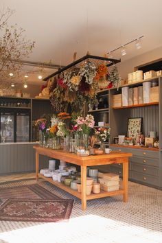 a flower shop with lots of flowers in vases and jars on the counter top