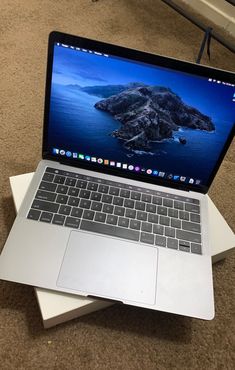 an open macbook pro laptop sitting on top of another apple laptop in a living room