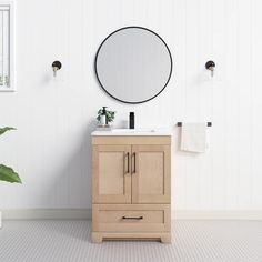 a bathroom vanity with a round mirror above it and a potted plant in the corner