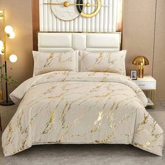 a bed with white and gold comforter in a bedroom next to a wall mounted clock