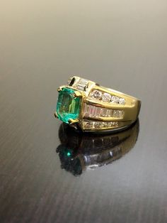 DeKara Designs Classic Handmade Art Deco Oval Emerald and Diamond Ring. Metal- 14K Yellow Gold, .583 Stones- 1 Emerald Cut Colombian Emerald 1.52 Carats, 18 Baguette Diamonds H-I, 16 Round Diamonds G-H Color VS2 Clarity 1.75 Carats. Size- 5 1/2. Free sizing. Art Deco Influenced Beautiful Colombian Emerald Diamond Engagement Ring. There is a beautiful 1.52 carat green emerald in the center of the ring that is emerald cut and expertly prong set. There are baguettes that are channel set on the side Yellow Gold Multi-stone Emerald Cut Diamond Ring, Yellow Gold Emerald Cut Multi-stone Ring, Anniversary Yellow Gold Multi-stone Emerald Ring, Formal Yellow Gold Multi-stone Emerald Ring, Yellow Gold Multi-stone Baguette Cut Rings, Heirloom Multi-stone Yellow Gold Wedding Jewelry, Multi-stone Baguette Cut Rings For Anniversary, Gold Multi-stone Baguette Cut Rings, Classic Multi-stone Princess Cut Jewelry