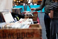 two people standing next to each other in front of a table full of records and cds