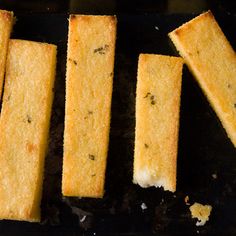 four pieces of bread sitting on top of a black tray next to a knife and fork