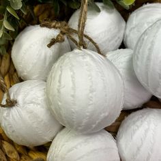 some white balls are sitting in a wicker basket with green leaves on the side