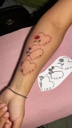 a woman's arm with two hearts and flowers tattooed on the left side of her arm