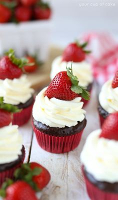 chocolate cupcakes with white frosting and fresh strawberries on top, ready to be eaten