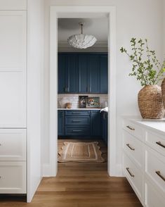 an open kitchen with blue cabinets and white counter tops, along with wooden flooring