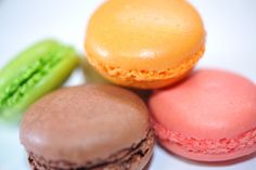 three different types of macaroons on a white plate with green, orange and pink