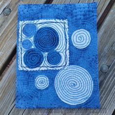 a blue and white square with circles on it sitting on a wooden table next to a piece of wood