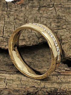 a gold wedding ring sitting on top of a piece of tree bark with diamonds in the middle