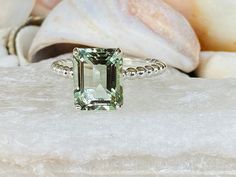 This beautiful solitaire setting contains a natural 3.50ct emerald cut prasiolite. The stone measures approximately 10x8mm. The band is 2mm wide and features beautiful beaded detailing. The ring is available in sterling silver, and 14k white, yellow, or rose gold. This ring makes a unique promise or engagement ring. Please send me a message if you need a size not listed. * This ring can be customized with any color center stone. All items are handmade by me in my shop in Manalapan, NJ. Please me Green Radiant Cut Engagement Ring, Large Wedding Rings, Crane Wedding, Green Engagement Rings, Emerald Engagement Ring Green, Prasiolite Ring, Clothing Board, Original Engagement Rings, Green Topaz