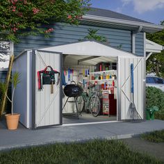 an outdoor storage shed with the door open and tools in it's center, next to a potted plant