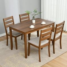 a dining room table with four chairs and a potted plant